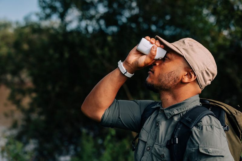 A man on a hike looking through a Canon PowerShot ZOOM.