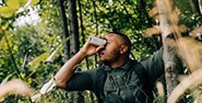 A man standing among the trees using the PowerShot ZOOM.