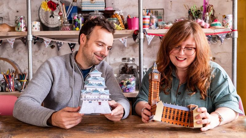 Creatieveling Paula Milner en haar man Dan houden papieren maquettes vast van een Japans kasteel en de Big Ben, gemaakt met sjablonen van Canon Creative Park.