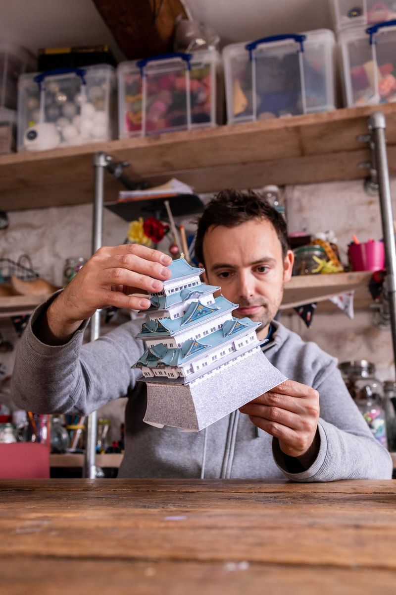 Een man houdt een geassembleerd Canon Creative Park-sjabloon van het kasteel van Nagoya in Japan vast en bewondert het.