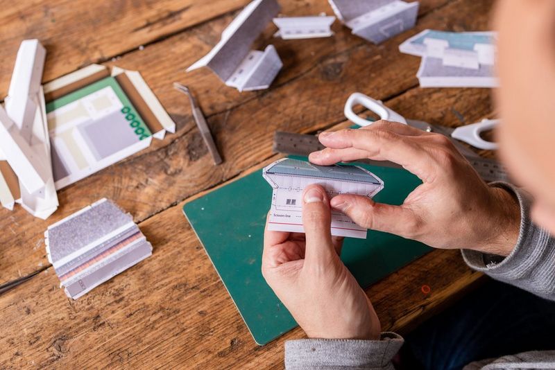 Handen die een liniaal en een schaar gebruiken om een deel van een Canon Creative Park-sjabloon uit te knippen.