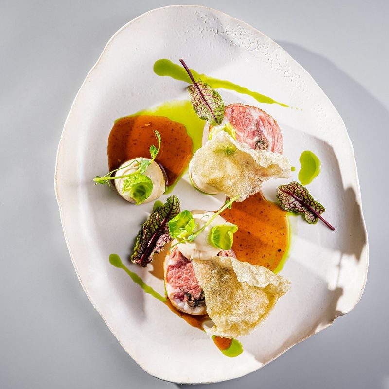 Een ovaal wit bord met verschillende gerechten in chili- en limoensaus gegarneerd met groene blaadjes.