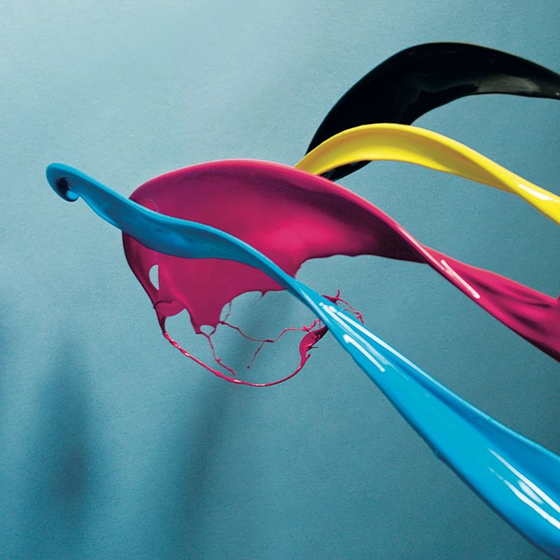 Bright blue, pink, yellow and black paint being thrown against a blue background