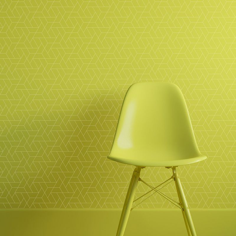Bright green plastic chair in front of a wall covered with digitally printed wallpaper in bright green with a fine-lined geometric print.