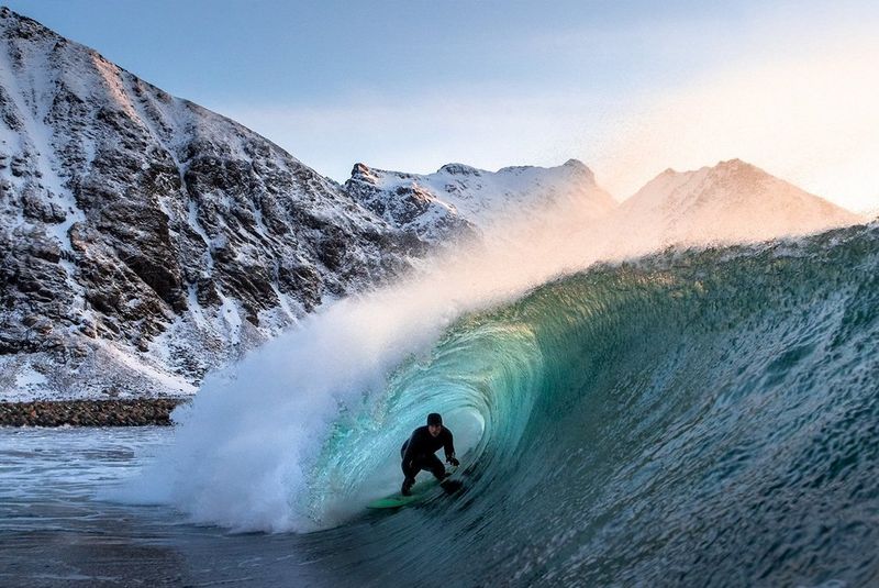 A surfer riding the wave in Arctic waters.