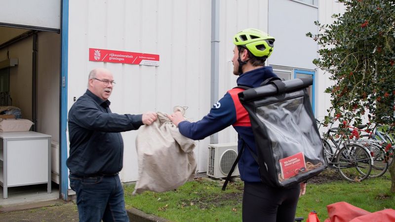 Fietskoerier van Cycloon komt de post brengen bij een locatie van de Rijksuniversiteit Groningen