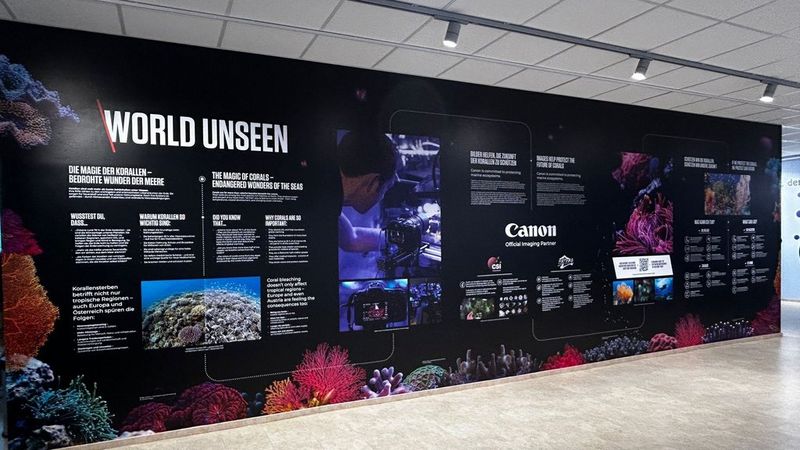 A large exhibition wall titled ‘World Unseen’ displays information panels and images about coral reefs and marine life.