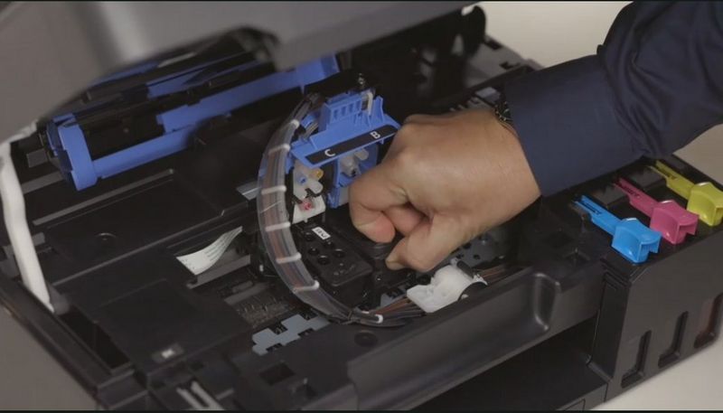 Een hand die de printkop van een Canon-printer vervangt.