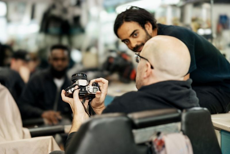 Cinematographer Korsshan Schlauer looks intently at a man in front of him who has his back to the camera.