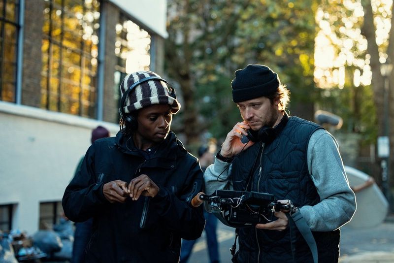 Filmmaker Samona Olanipekun confers with a man wearing headphones and carrying a piece of recording equipment around his neck.