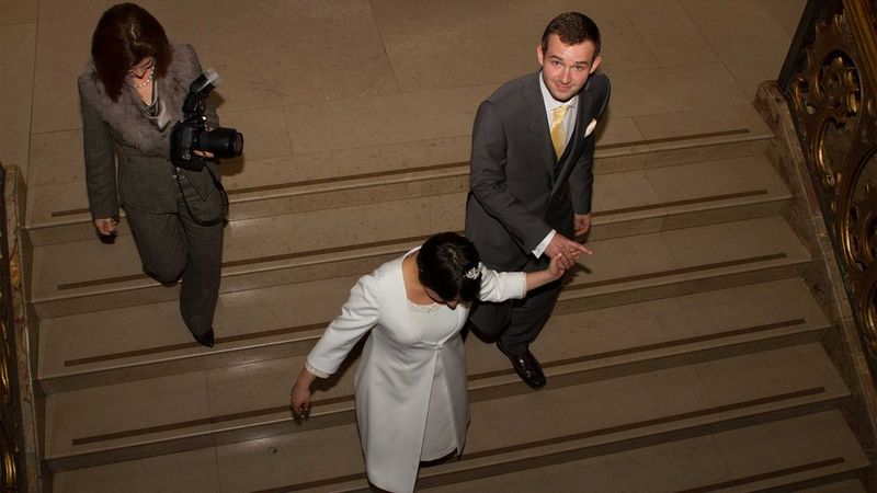 A bride and groom walking down a staircase with their photographer.