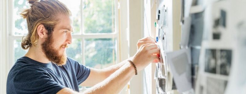 Man pinning print onto wall