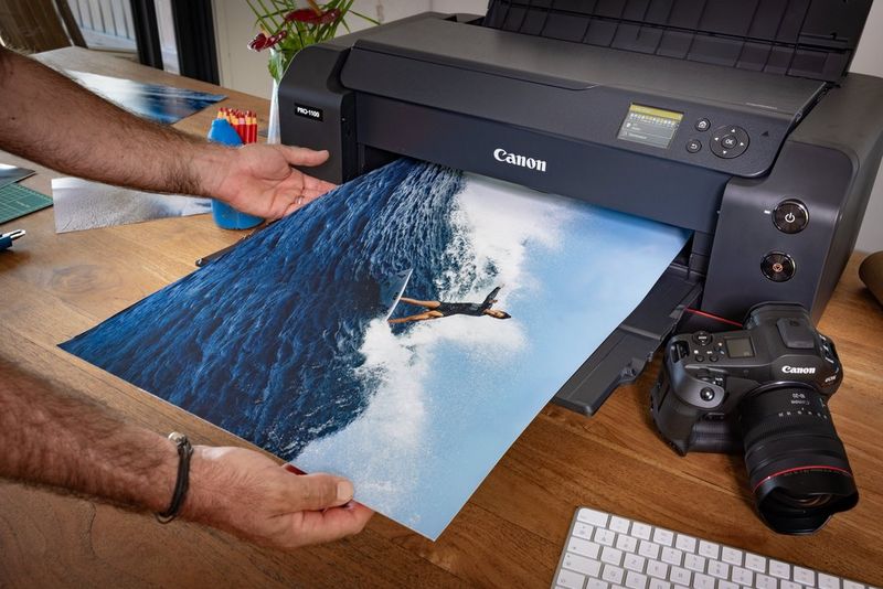 Een persoon die een grootformaat print uit een Canon-printer haalt.