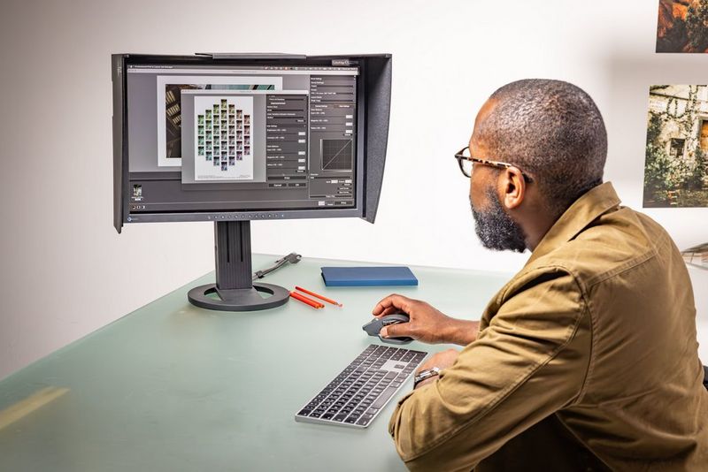 A man looking at a computer monitor displaying Canon’s Professional Print & Layout software on screen. 