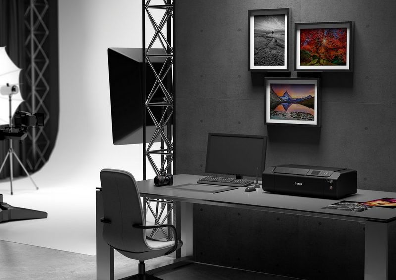 Фотопринтер Canon imagePROGRAF PRO-300 стоит на столе в преимущественно черно-белой фотостудии. Рядом с ним — ноутбук и несколько ярких печатных фотографий.