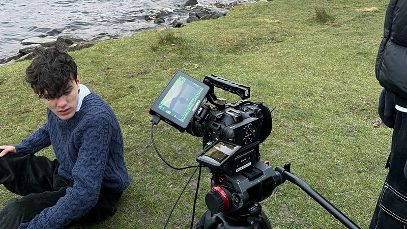 Canon EOS C70 camera filming a boy sat on the grass in front of a lake