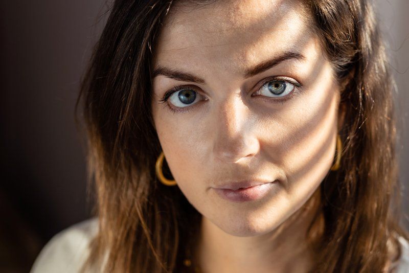 A portrait of a woman with light bars shining across her face.