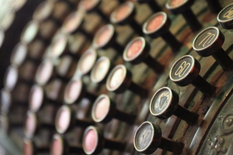 A view of the keys of an old cash register, with only the very closest column of keys in sharp focus and the rest of the image blurred.