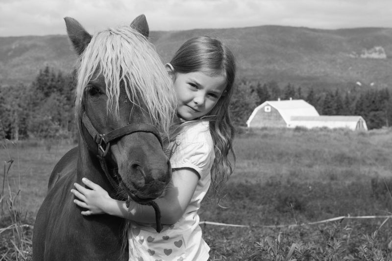 The same shot of a girl hugging a pony with the Monochrome Picture Style applied, producing a crisp black and white image.