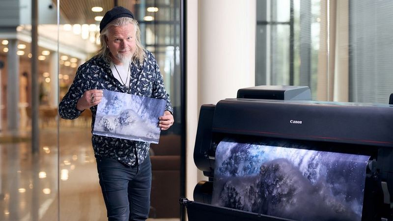 Palkittu luontovalokuvaaja Juha Metso esittelee tulostettua kuvaansa murtuvasta jäävuoresta. Kuvan etualalla Canon suurkuvatulostin.