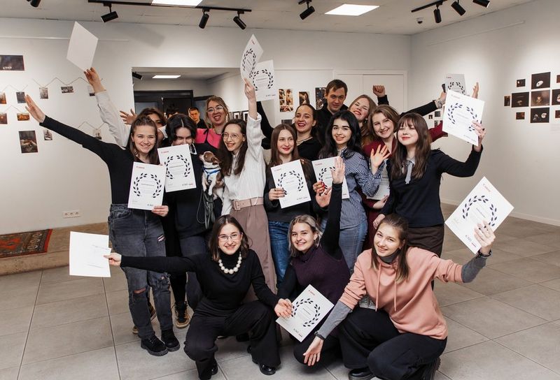A group of smiling young people hold up certificates.