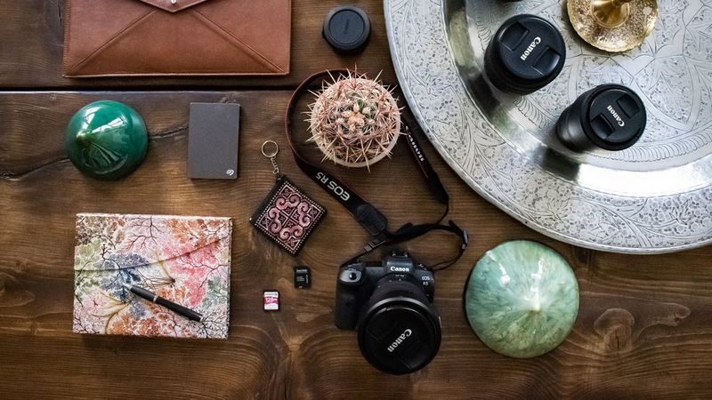 A Canon EOS R5 camera, Canon lenses, a memory card, notebook, and accessories.