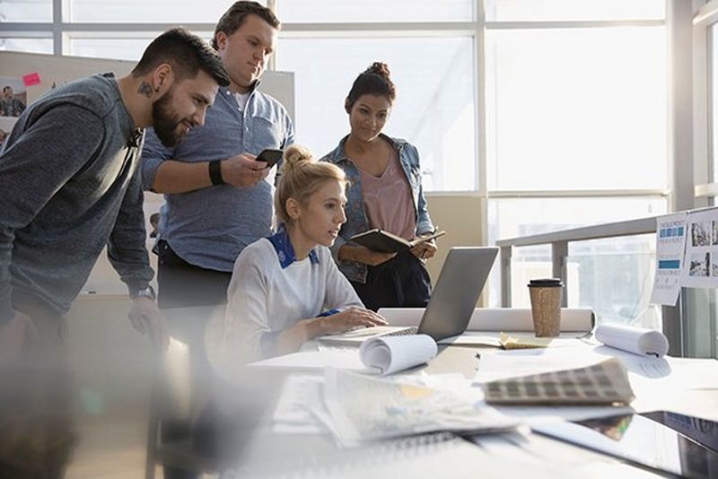 4 kolleager kigger på en computer og læser om Canons kommunikationsløsninger