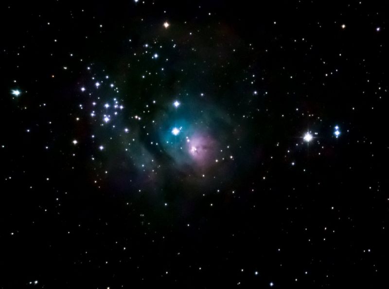 A field of stars with a prominent nebula in the centre.