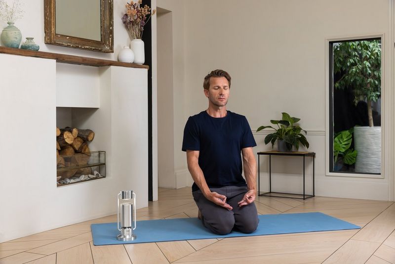 Iemand knielt op een yogamat naast een Canon Speakerlamp ML-A.