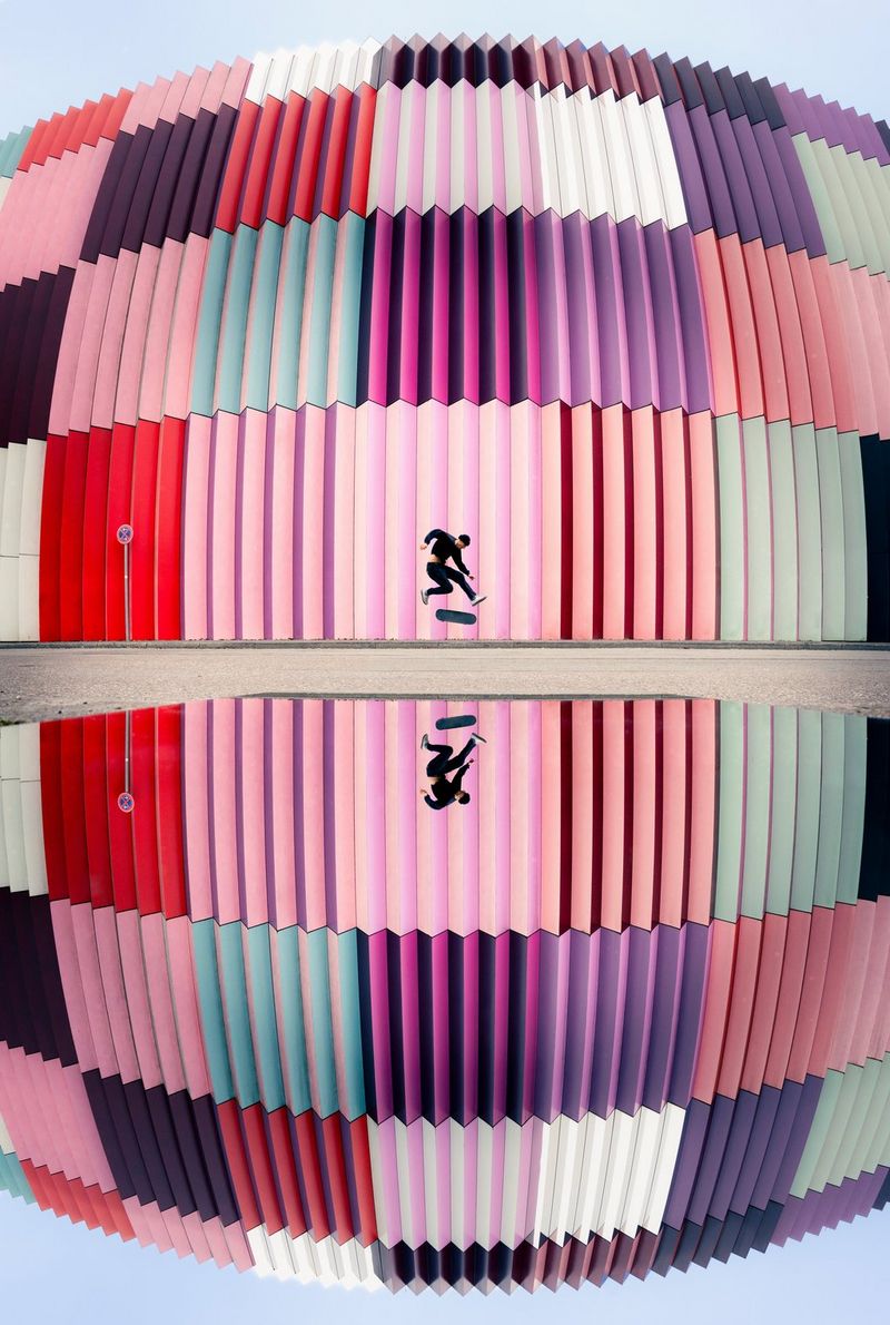 A fisheye image of a skateboarder performing a trick against a colourful building, reflected in a mirror. Action photo taken by Lorenz Holder on a Canon EOS R5 Mark II with a Canon RF 7-14mm F2.8-3.5L FISHEYE STM lens.