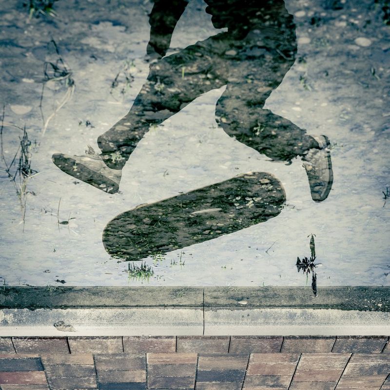 A reflected image of a skateboarder's legs and skateboard, which is being flipped mid-trick. Action photo by Lorenz Holder taken on a Canon EOS R5 Mark II with a Canon RF 28-70mm F2L USM lens.