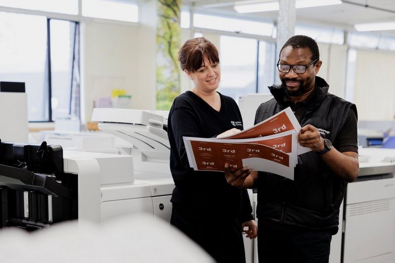 Lifestyle-Bild, das zwei Personen in der Universität zeigt, die Druckaufträge prüfen