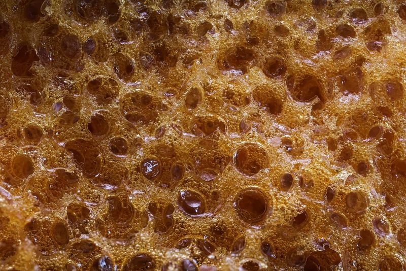 Запечатленный крупным планом в макрорежиме медовый батончик с множеством воздушных пузырьков. Снято на камеру Canon EOS R10 с объективом Canon RF 100mm F2.8L MACRO IS USM.