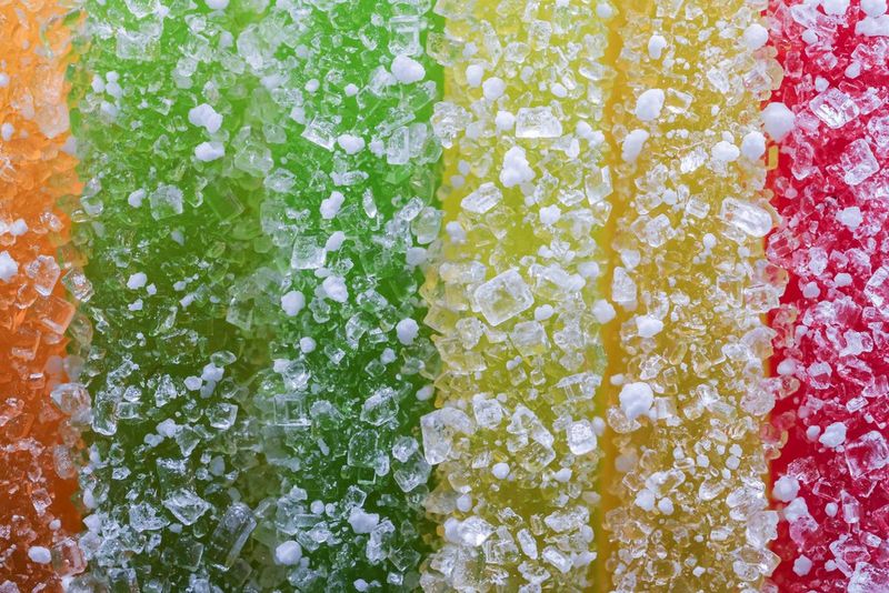 Макрофотография красочных мармеладных полосок, снятая при увеличении 1:1 на камеру Canon EOS R10 с объективом Canon RF 100mm F2.8L MACRO IS USM.