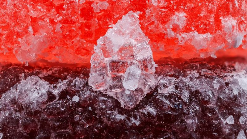 Запечатленные крупным планом в макрорежиме два кусочка фруктовой пастилы с большим кусочком сахара перед ними в форме капли. Снято на камеру Canon EOS R10 с объективом Canon RF 100mm F2.8L MACRO IS USM.