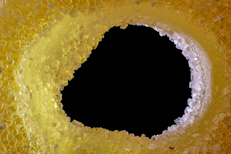 Makro záber na cukrovinku v tvare cumľa osvetlenú tak, aby boli vidieť kryštály na boku otvoru. Nasnímané fotoaparátom Canon EOS R10 s objektívom Canon RF 100 mm F2.8L MACRO IS USM.