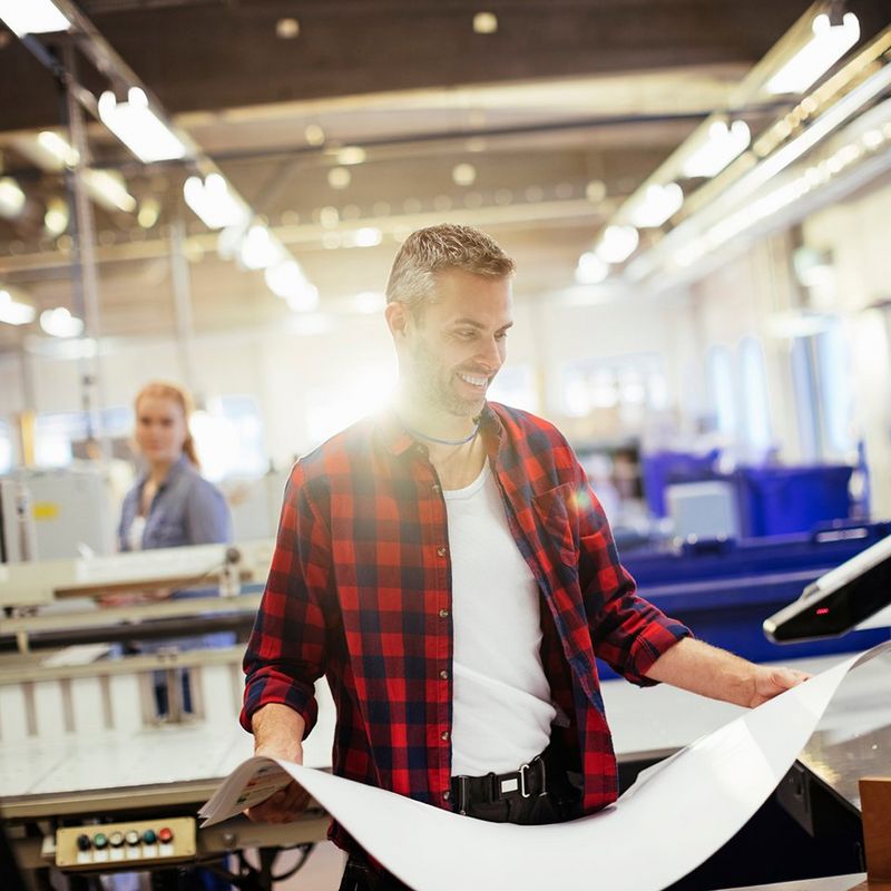 En mand på et trykkeri kigger på et print som er printet på Canon-udstyr med hjælp af Canons softwareløsninger