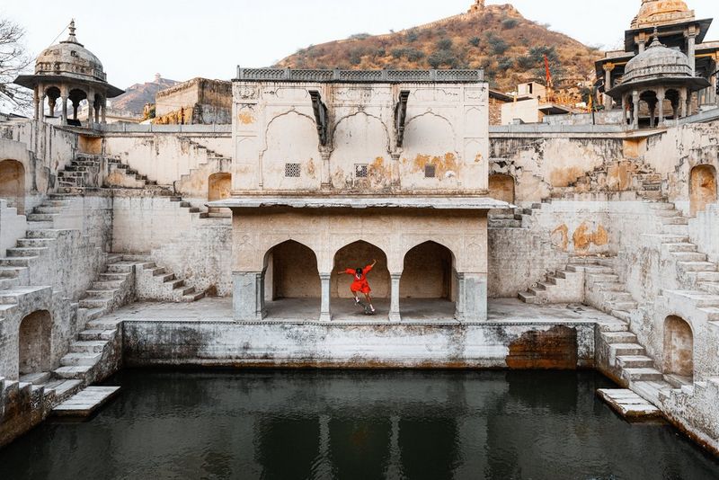Action photograph of a female skateboarder dressed in red doing a trick at the Panna Meena Kund stepwell in Jaipur, India captured by Martin Bissig on the Canon EOS R5 Mark II.