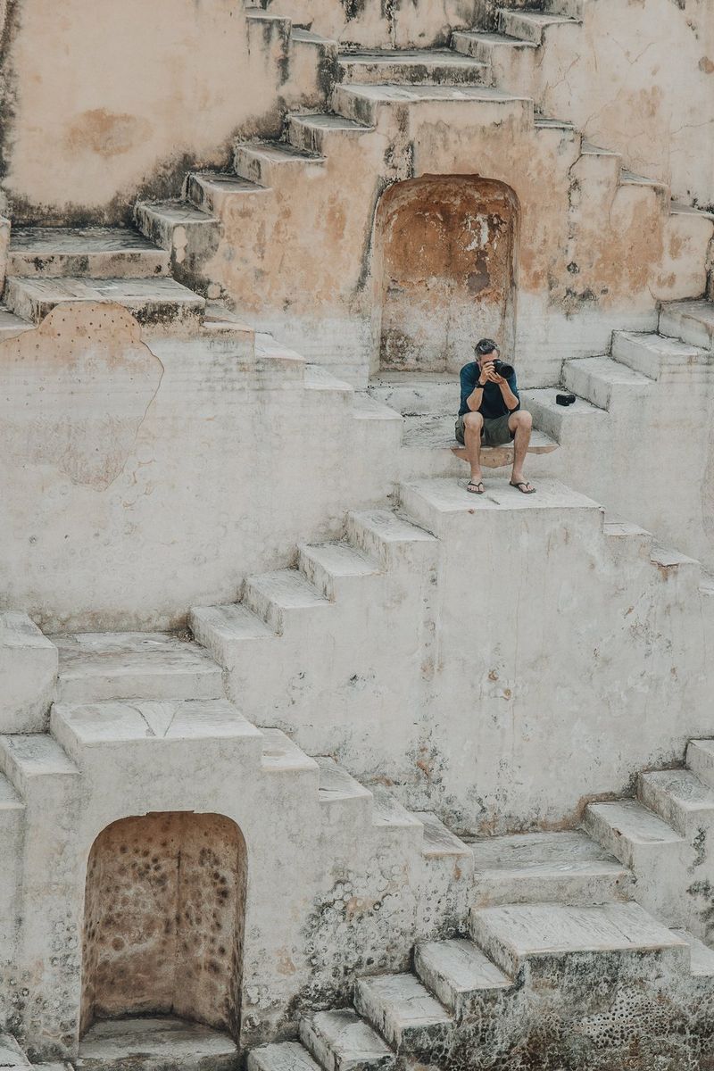 Behind the scenes image of photographer Martin Bissig sitting taking a photo using his Canon EOS R5 Mark II at the Panna Meena Kund stepwell in Jaipur, India.