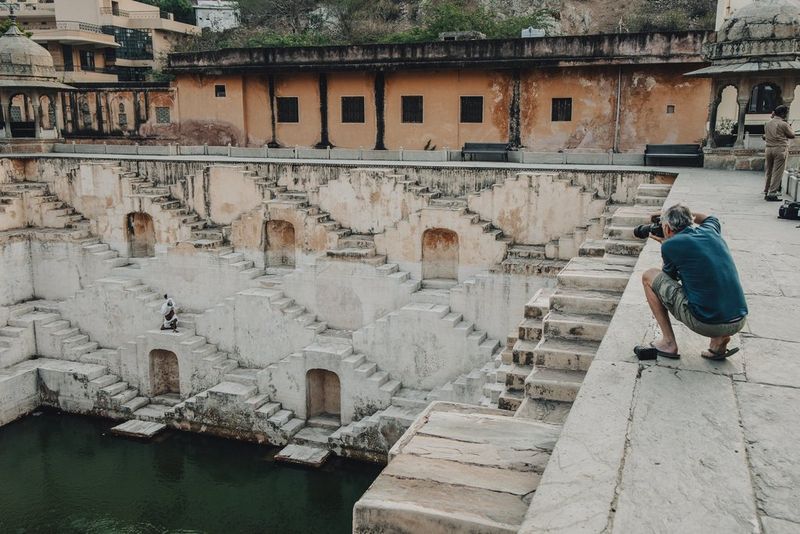 Behind the scenes image of photographer Martin Bissig taking a photo of a skateboarder using his Canon EOS R5 Mark II at the Panna Meena Kund stepwell in Jaipur, India.