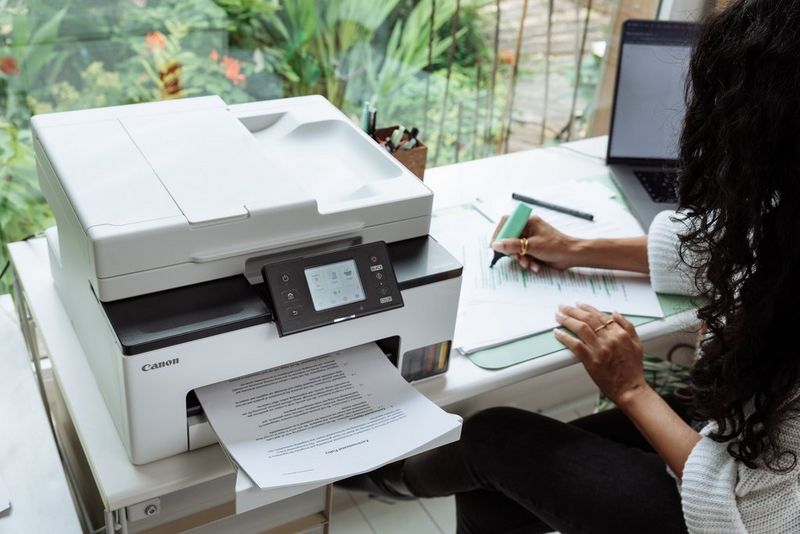 Женщина использует текстовыделитель на печатном документе, а на столе рядом с ней можно увидеть принтер Canon «Формула выгодной печати».