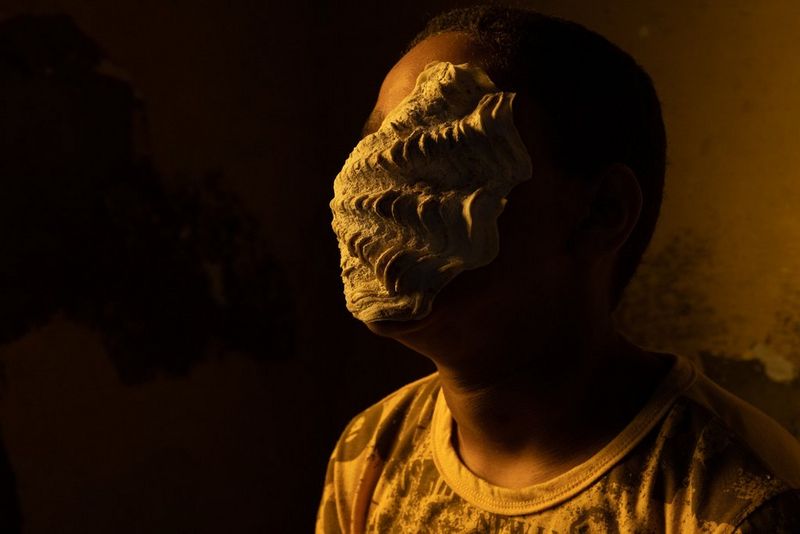 A person with a shell covering their face. Shot on Canon.