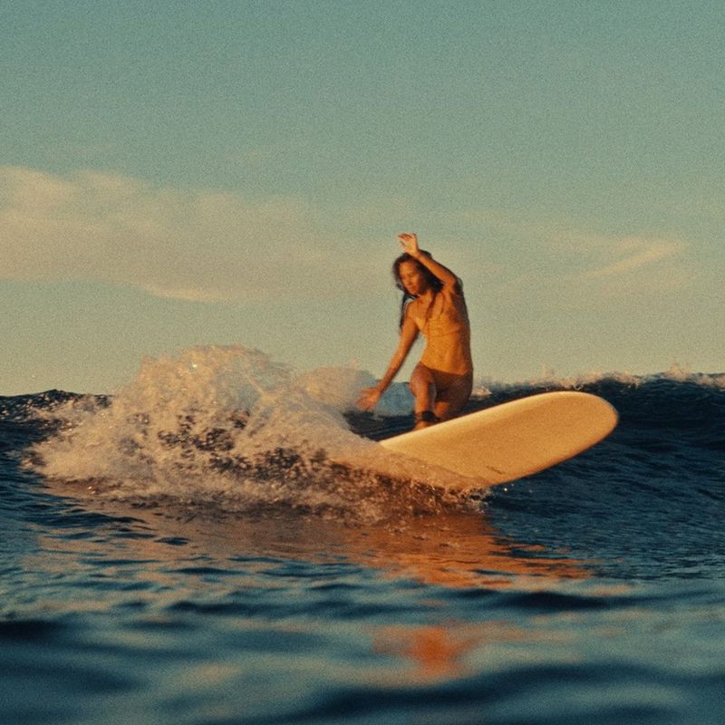 Photo d’une femme sur sa planche de surf en train de surfer une vague