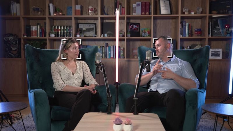 Two people sitting in easy chairs recording a vlog, with an auto tracking frame on each face from the Canon PTZ camera recording them.