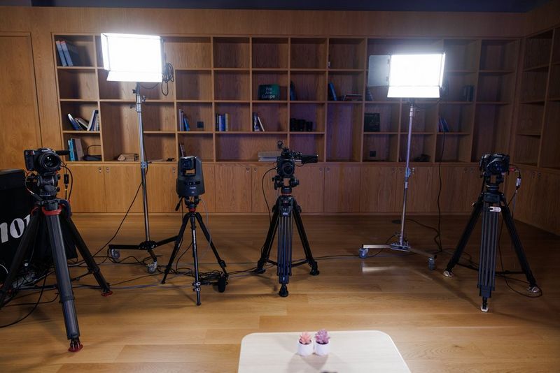 Een podcaststudio met vier Canon-camera's en -objectieven op statieven, plus twee grote kunstmatige lichtbronnen.
