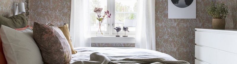 A recreated 18th century wallpaper with patterns of Lily of the Valley is used in a modern bedroom interior.