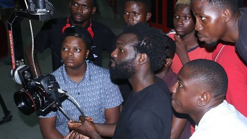 A group of students gather round a Canon pro video camera