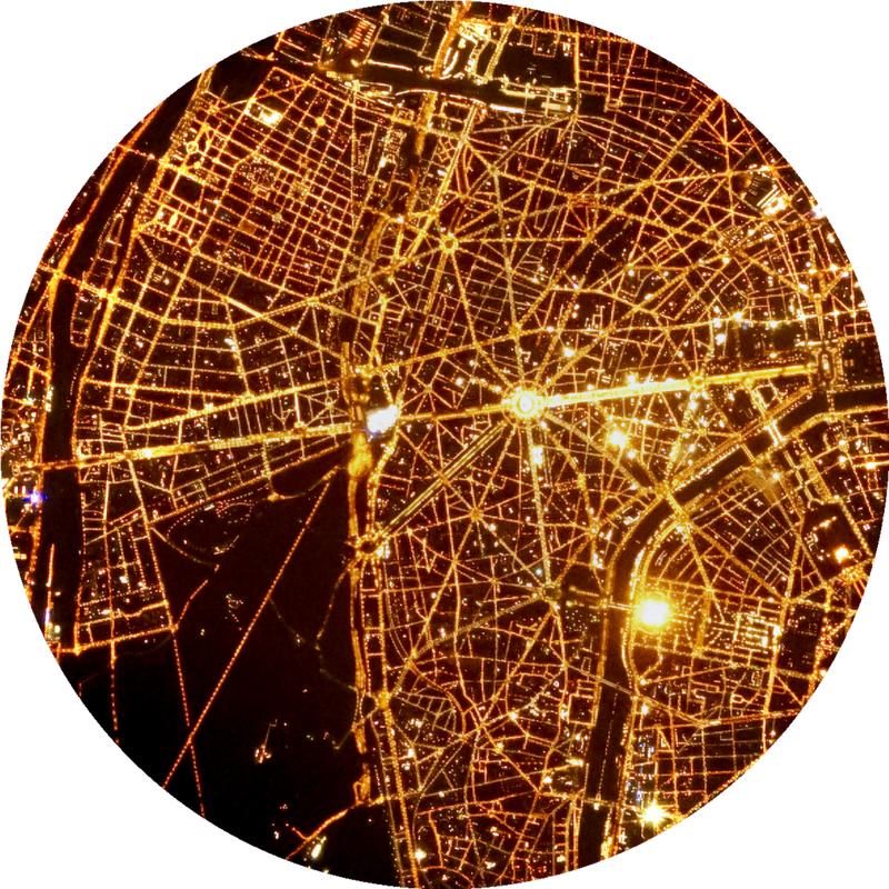 A satellite view of Paris at night, illuminated by countless lights.