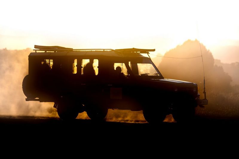 A car surrounded by dust from the road.
