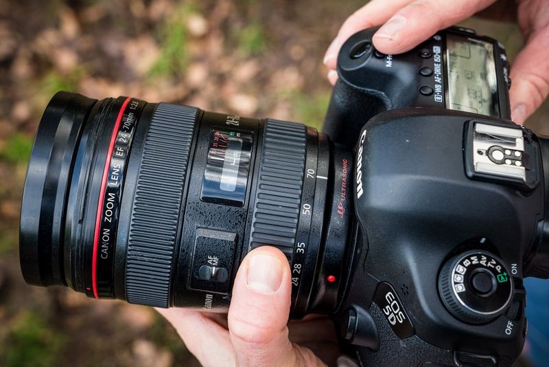 The same photographer adjusting focal length of the lens.